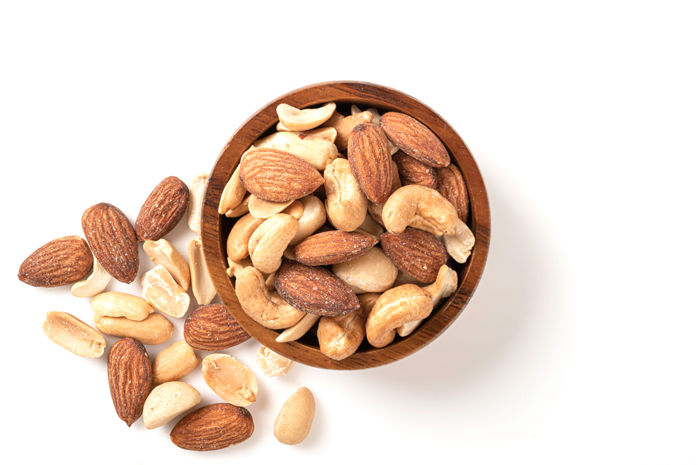 Cashews vs. Almonds. Top view Mixed of nut in wooden bowl isolated on white background.