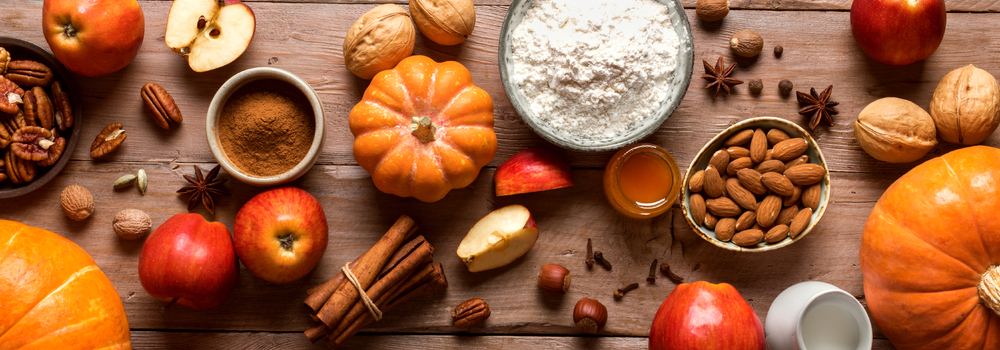 Autumn fall baking background with pumpkins, apples, and holiday nuts